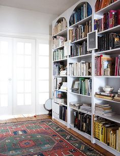 a book shelf filled with lots of books on top of a wooden floor next to a doorway