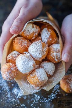 powdered sugar covered donuts in a paper bag