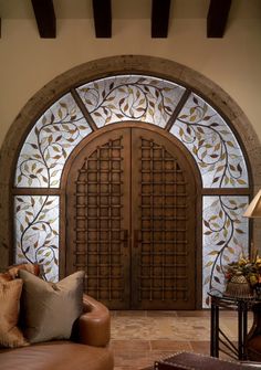 a living room filled with furniture and a large arched window above the doorway to an outside patio