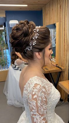 a woman in a wedding dress looking at herself in the mirror with her hair pinned back into a low bun