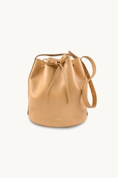 The Anne Leather Bucket Bag in almond is a stylish and versatile accessory that is perfect for any occasion. Crafted from soft 100% leather, this bag is both durable and luxurious. With its spacious interior and adjustable strap, it offers plenty of room for all your essentials while providing comfort and convenience. The almond color adds a touch of elegance to any outfit, making it a must-have accessory now and for many seasons to come. Made in Portugal.Measures: 22 cm x 20 cm x 13 cm The nobi Almond Color, Tiny Cottons, Outfit Making, Buckle Sandals, Leather Bucket Bag, Leather Bucket, Bucket Bag, 20 Cm, Adjustable Straps