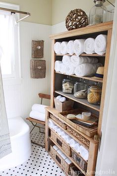 a white bathroom with black and white tile flooring, an old fashioned cabinet in the corner