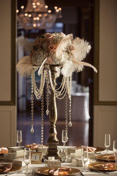 a fancy centerpiece with feathers and beads on a table in a formal dining room