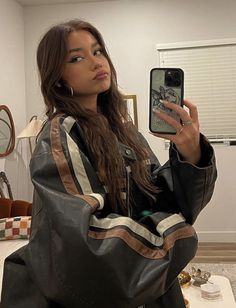 a woman taking a selfie with her cell phone in a room filled with furniture