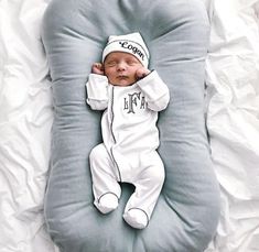 a baby laying on top of a pillow in the shape of a beanie hat