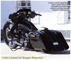 a black motorcycle parked in front of a white building with the words american bagger magazine written below it