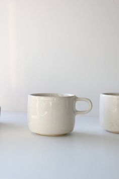 two white cups sitting next to each other on a table