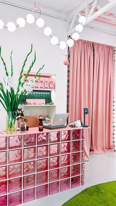 an office with pink and green decor in the corner, along with a large window