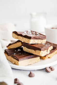 chocolate and peanut butter bars stacked on top of each other with milk in the background