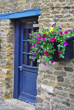 a blue door and window with flowers in the planter on the side of it