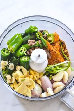 a food processor filled with lots of different types of vegetables and seasoning in it