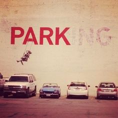 a parking lot with cars parked in front of it and the word park painted on the wall