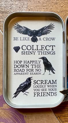 a small metal tray with some type of bird on it's side and the words, be like a crow collect shiny things