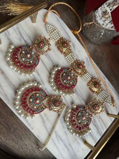 This elegant choker in the vintage nauratan style is perfect for wearing to engagement parties, valima, nikkah, mehndi ceremonies, and bridal showers. Nauratan, which translates to "nine colors" in Hindi and Urdu, is a well-liked traditional jewellery design that is frequently worn by Indian and Pakistani citizens. This jewellery set is embellished with tiny, nine pastel-colored beads on every piece. This set is elegantly presented in a sliding box that may be given as a gift. About this item: T Mehndi Jewellery Pakistani, Luxury Multicolor Meenakari Sets, Round Wedding Tikka For Festivals, Temple Jewelry Tikka With Stone Work For Reception, Round Choker For Wedding And Festivals, Temple Jewelry For Wedding On Eid, Wedding Jewelry For Eid With Tilla Detail, Round Tikka For Wedding And Festivals, Traditional Bridal Sets With Intricate Design For Reception