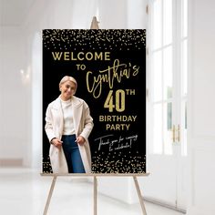 a woman standing in front of a black and gold birthday sign