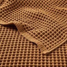 a close up view of a brown knitted blanket with holes in the middle and sides