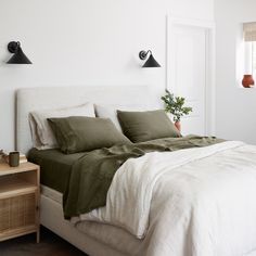 a bed with two lamps on the wall above it and a plant in a pot