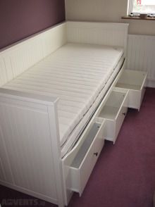 a white bed with drawers underneath it in a room next to a purple carpeted floor