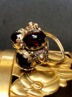 A lovely vintage ring done in 14K yellow gold with pierced gold work set with approximately 12cttw between three large cabochon garnets. Ring is circa late 1960's. Dimensions/Weight: Ring measures .70" by .95" and weighs 8.6g. Size 4.5 (sizable). Condition: All stones are secure and undamaged. Perfectly wearable condition. R-E Antique Dome Ring Stamped 14k As Gift, Vintage Gold Domed Ring, Antique Gold Domed Ring, Antique Domed Gold Ring, Victorian Gold Domed Rings, Gold Domed Collectible Ring, Victorian Domed Gold Rings, Vintage Yellow Gold Dome Ring For Wedding, Vintage Oval Dome Ring For Wedding