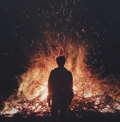 a man standing in front of a fire with lots of sparks coming out of it