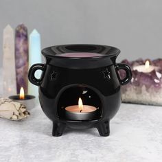 a black caulder sitting on top of a table next to candles and other items