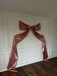 a room with white walls and wooden floors, decorated with pink satin draping