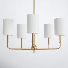 a brass chandelier with white lamps hanging from it's sides and four shades on each lamp