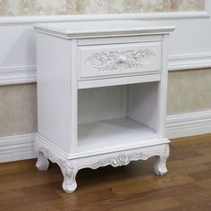 a small white cabinet sitting on top of a hard wood floor next to a wall