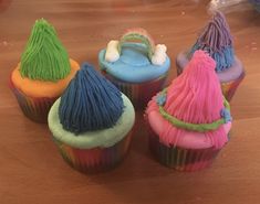 cupcakes decorated with different colored frosting on a wooden table in the shape of christmas trees