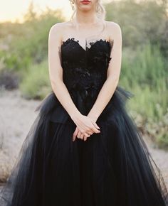 a woman in a black dress is posing for the camera