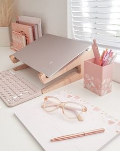 a laptop computer sitting on top of a desk next to a keyboard and pen holder