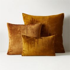 three gold velvet pillows sitting on top of each other