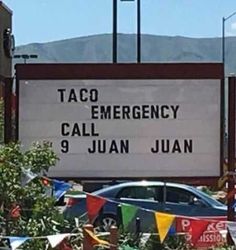 a sign that says taco emergency call 9 juan juan in front of some cars