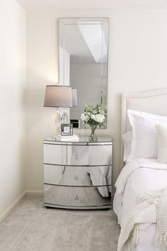 a bedroom with a mirrored dresser and white bedding