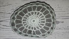 a crocheted doily sits on a wooden surface