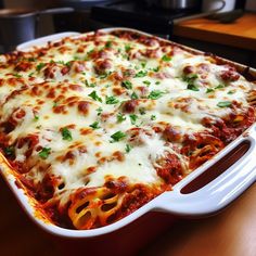 a casserole dish with meat and cheese in it sitting on a wooden table