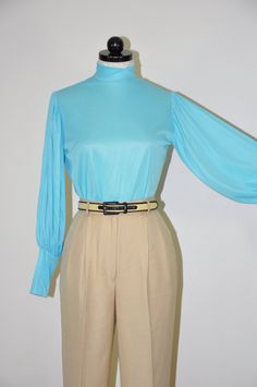 "Gorgeous vintage 1960s - 1970s turquoise blouse with high neckline, zipper back closure, long bishop sleeves with wide cuffs cuffs and slim fit. Super lightweight, soft and silky poly fabric, unlined, sheer. Original tags attached. M E A S U R E M E N T S  (taken flat, unstretched) size on tag: vintage 11-12 / please see measurements below for a perfect fit fits like: approx. XS / S bust (armpit to armpit): 19\" / 48m (x2) waist (at narrowest part): 18\" / 46cm (x2) back (left to right shoulder seam): 14\" / 35.5cm sleeve length (shoulder to cuff): 23\" / 58.5cm length (shoulder to hem): 23\" / 58.5cm fabric: 100% Celanese Fortrel polyester color: blue brand / maker: Cheeky Knits for Lady Manhattan condition: excellent vintage / original tags attached * * * * * * Additional TOPS & SHIRTS: Turquoise Blouse, Statement Blouse, Bishop Sleeve, Wide Cuff, Sheer Blouse, Blue Blouse, High Neckline, Vintage 1960s, Top Shirt