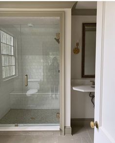 a bathroom with a walk in shower next to a white sink and mirror on the wall