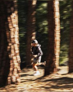 a man running through the woods with trees in the foreground and blurry background