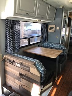 the interior of an rv with wood flooring and blue curtains on the windowsill