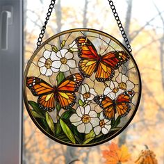 a stained glass sun catcher hanging from a window with flowers and butterflies on it's side