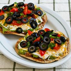 two pieces of pizza with olives and peppers on it sitting on a white plate