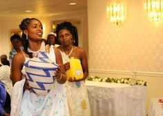 two women dressed in white and blue holding yellow jugs