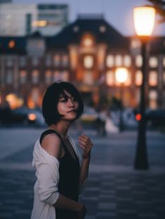 a woman standing in front of a street light with her hand on her chest and looking up at the sky