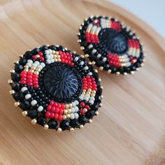 two black, red and white beaded earrings sitting on top of a wooden tray