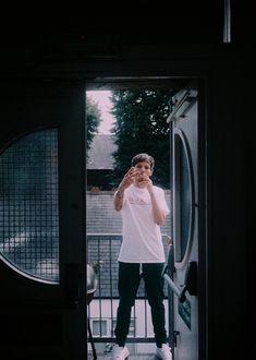 a man standing in front of a door talking on a cell phone