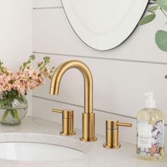 a bathroom sink with gold faucet and soap dispenser next to it