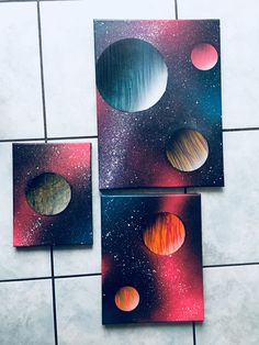 three pieces of art with planets on them sitting on a tile floor next to each other