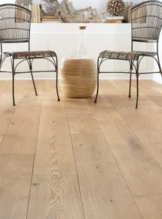 two chairs sitting next to each other on top of a hard wood floor in front of a fireplace