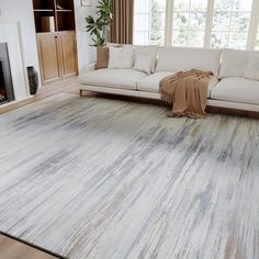 a living room filled with furniture and a large rug on top of a hard wood floor